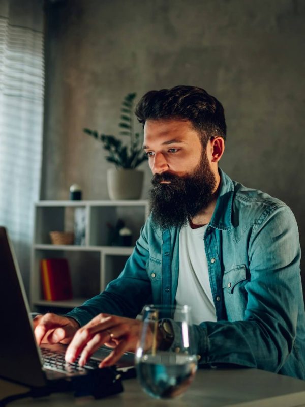 an operating data security worker is working from his darkened home office remotely .jpg